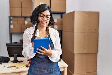 Young latin woman ecommerce business worker using touchpad at office