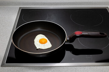 frying pan on the hob with fried eggs from one egg with yolk