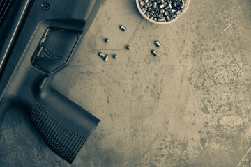 pneumatic shooting.an air rifle and bullets on a steel table. A black air rifle lies against the...