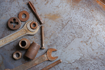 Old wrenches, socket wrenches, bolts and nuts on a steel sheet background