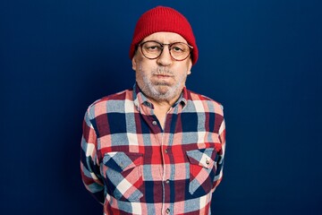 Handsome mature man wearing hipster look with wool cap puffing cheeks with funny face. mouth inflated with air, crazy expression.