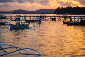 Beautiful colorful sunset on the seashore with fishing boats. Philippines, Siargao Island.