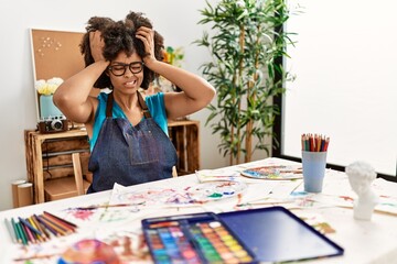 Beautiful african american woman with afro hair painting at art studio suffering from headache desperate and stressed because pain and migraine. hands on head.
