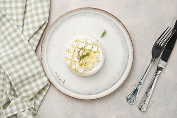 Oven baked camembert cheese with lye baguette bread on white plate, grey concrete surface. Homemade...