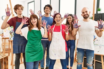 Fototapeta premium Group of people showing painted palm hands looking to the camera standing at art studio.