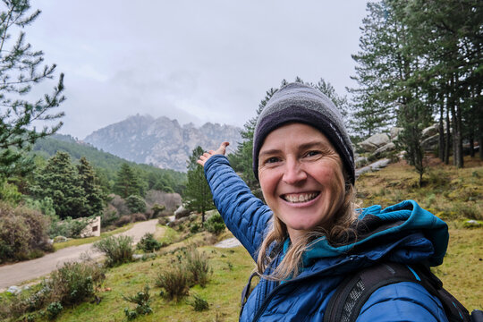 A happy beautiful woman taking a selfie portrait with smartphone on mountain at winter.
