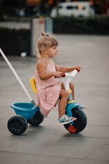 little child playing with a tricycle 