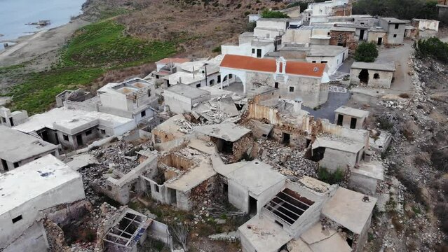 Village ruins, only Church building unbroken, camera fly over old Sfendyli settlement, flooded and destroyed buildings on hill side.