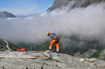 A man working on a rock in the mountains above a deep valley (Norway)	