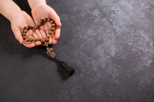 Child's hands holding the wooden cross and beads th in the shape of a heart.
