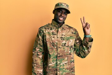 Young african american man wearing army uniform smiling with happy face winking at the camera doing victory sign with fingers. number two.