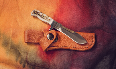 A knife with leather sheath on cotton fabric abstract background