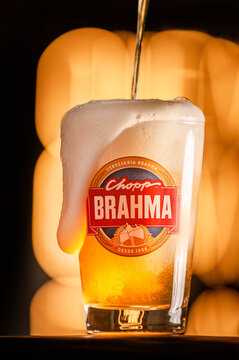 Pouring draft beer Brahma in a glass on illuminated signs background.