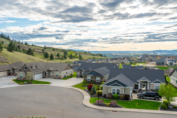 Fototapeta na wymiar View from a hilltop in Liberty Lake, Washington, of a newer subdivision of homes with the cities of Spokane and Spokane Valley. in the distance.