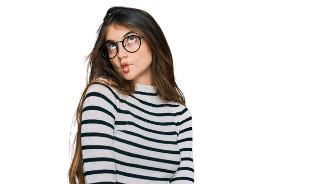 Young beautiful teen girl wearing casual clothes and glasses making fish face with lips, crazy and comical gesture. funny expression.