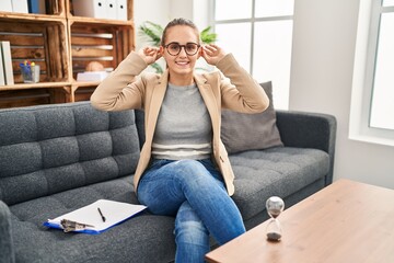 Young woman working at consultation office smiling pulling ears with fingers, funny gesture....