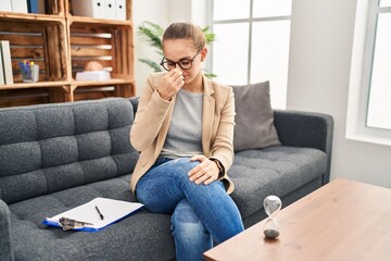 Fototapeta premium Young woman working at consultation office tired rubbing nose and eyes feeling fatigue and headache. stress and frustration concept.