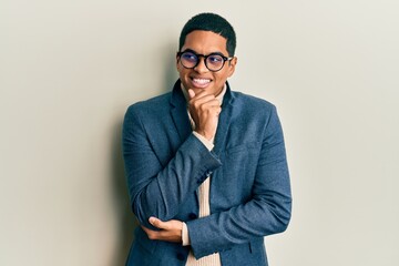 Young handsome hispanic man wearing elegant clothes and glasses with hand on chin thinking about...