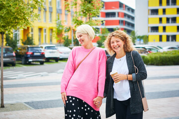 Two women friends laughing and hugging outdoors.