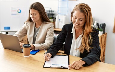 Mother and daughter business workers smiling confident working at office