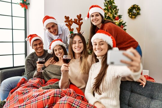 Group of young people celebrating christmas make selfie by the smartphone sitting on the sofa at home.
