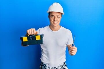 Handsome young man holding toolbox and screwdriver smiling with a happy and cool smile on face. showing teeth.