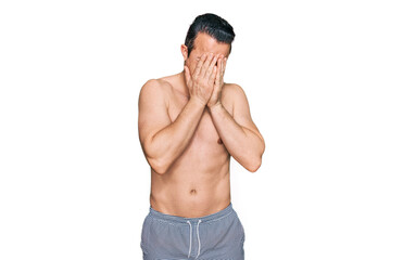 Fototapeta premium Handsome young man wearing swimwear shirtless with sad expression covering face with hands while crying. depression concept.
