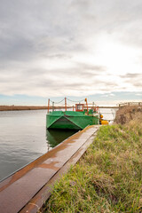 Generic green metal workboats moored on the river bank on the River Bure, Norfolk Broads