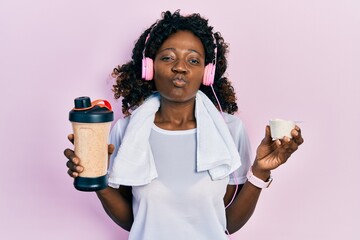 Young african american woman wearing sport clothes drinking a protein shake looking at the camera...