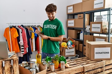 Young arab man wearing volunteer uniform writing on clipboard at charity center