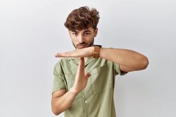 Young arab doctor man standing over isolated background doing time out gesture with hands,...