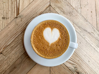 A mug of flat white or latte art coffee on a wooden background. Coffee art. Heart flower shape latte art