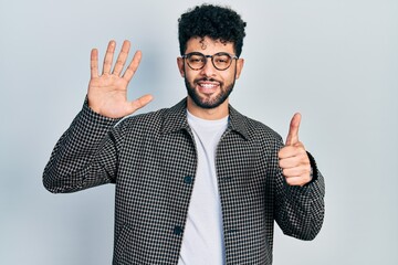 Young arab man with beard wearing glasses showing and pointing up with fingers number six while smiling confident and happy.