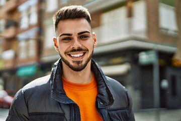 Handsome hispanic man with beard smiling happy and confident at the city wearing winter coat