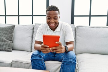 Young african man using touchpad device at home