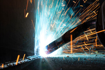 Close up view gas metal arc welding (GMAW) process with sparks, light and smoke. It is a...