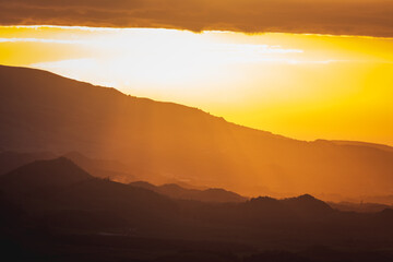 Fototapeta na wymiar Sunrise over landscape with mountains, orange light, sun rising.
