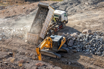 White color excavation dump truck is unloading to rocks in the construction site.  © Funtay