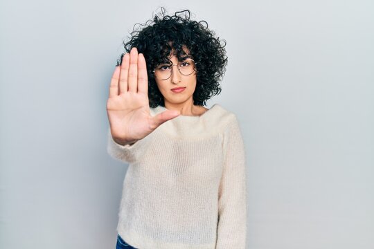 Young middle east woman wearing casual white tshirt doing stop sing with palm of the hand. warning expression with negative and serious gesture on the face.