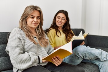 Young couple reading book sitting on the sofa at home.