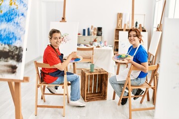 Two artist student women smiling happy painting at art school.