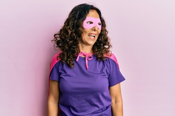 Middle age hispanic woman wearing super hero costume looking to side, relax profile pose with...