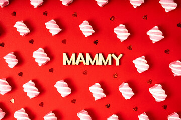 Mothers Day. A pattern of small marshmallows and glitter in the shape of a heart with the inscription "mammy" on a red background.