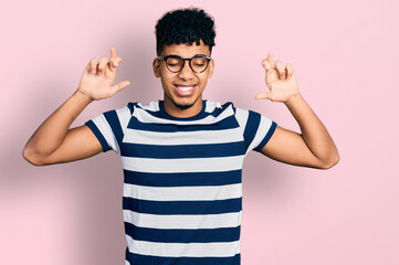 Fototapeta premium Young african american man wearing casual clothes and glasses gesturing finger crossed smiling with hope and eyes closed. luck and superstitious concept.