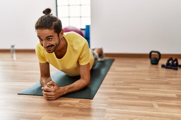 Handsome hispanic man training doing plank at the gym