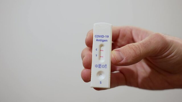 Home antigen test for Covid-19 coronavirus with positive result with two lines. Hand shows camera positive self testing device for non-medical personnel use. Quick and fast results for home check