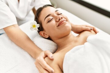 Young latin woman relaxed having shoulders massage at beauty center