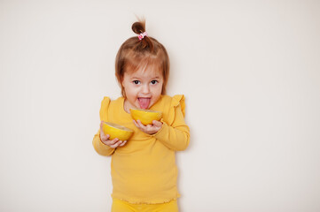 Baby girl in yellow with lemon, isolated background.