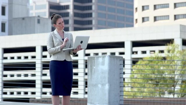 Businesswoman using laptop in modern cityscape