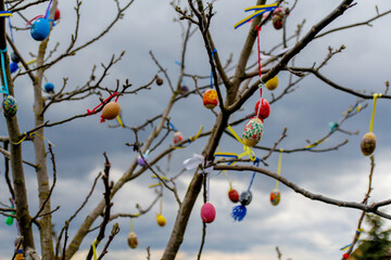 Many Easter eggs decorated. Handmade diy home exterior decoration with colorful easter eggs hanging on spring branches tree. Creativity craft concept. Ukrainian flag. Outside. Easter background